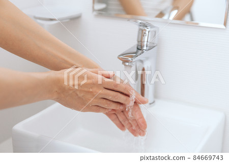 Washing hands under the flowing water tap. Hygiene concept hand detail. Washing hands rubbing with soap for corona virus prevention, hygiene to stop spreading corona virus in or public wash room. 84669743
