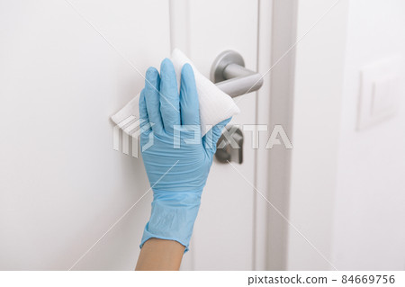 Cleaning black door handles with an antiseptic wet wipe and blue gloves. Sanitize surfaces prevention in hospital and public spaces against corona virus. Woman hand using towel for cleaning. Cleaning black door handles with an antiseptic wet wipe and blue gloves. Sanitize surfaces prevention in hospital and public spaces against corona virus. Woman hand using towel for cleaning. 84669756
