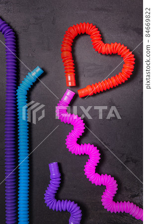 Tube toys bent as heart balloon and wavy ribbon on black concrete Tube toys bent as heart balloon and wavy ribbon on black concrete 84669822