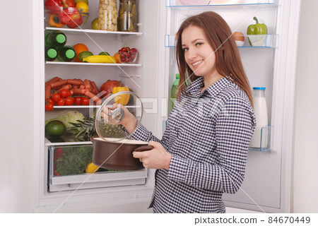 Satisfied housewife near filled fridge. 84670449