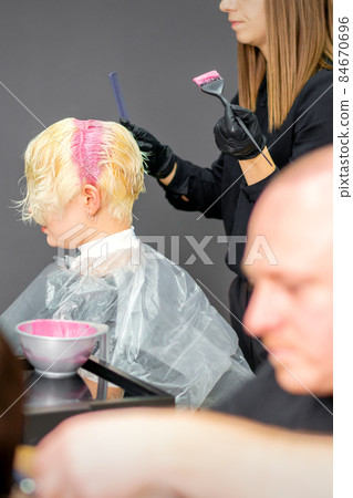 Coloring female hair in the hair salon. Young woman having her hair dyed by beautician at the beauty parlor. 84670696