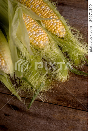 Fresh Raw Corn on Cobs on an old wooden table. Autumnal harvest background in a dark mood. 84671340
