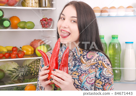 Portrait of a girl with a red hot pepper. Portrait of a girl with a red hot pepper. 84671443
