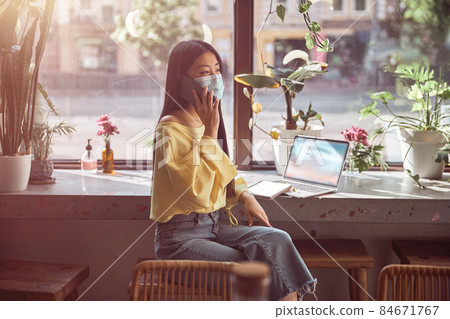 Young woman in protective mask working in cafe 84671767