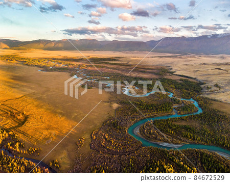The Kurai steppe and the Chuya River against the background of the North Chuya ridge. Altai, Russia. Panoramic image from an aerial drone. The Kurai steppe and the Chuya River against the background of the North Chuya ridge. Altai, Russia. Panoramic image from an aerial drone. 84672529