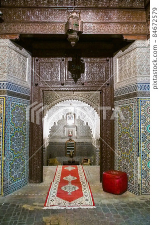 Ornate carved wood and brass entrance of a restaurant with tile steps in the medina of Marrakech, Morocco 84672579