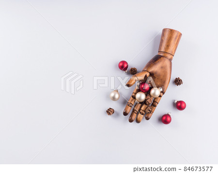 Wooden hand with christmas red and golden ornaments on gray Wooden hand with christmas red and golden ornaments on gray 84673577