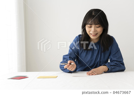 一個女人在寫留言卡,在辦公桌前送禮物 一個女人在寫留言卡,在辦公桌前送禮物 84673667