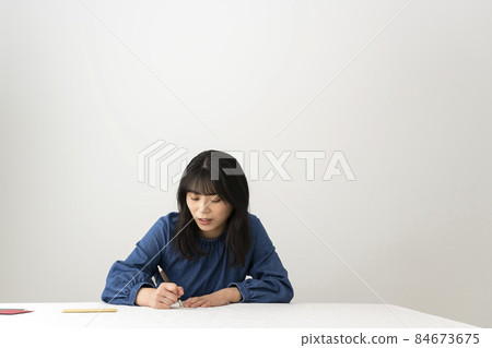 A woman writing a message card to give with a gift at the desk 84673675
