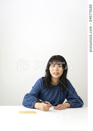 一個女人在寫留言卡,在辦公桌前送禮物 一個女人在寫留言卡,在辦公桌前送禮物 84673686