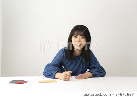 一個女人在寫留言卡,在辦公桌前送禮物 一個女人在寫留言卡,在辦公桌前送禮物 84673687