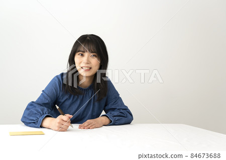 一個女人在寫留言卡,在辦公桌前送禮物 一個女人在寫留言卡,在辦公桌前送禮物 84673688