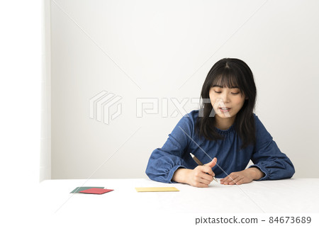 一個女人在寫留言卡,在辦公桌前送禮物 一個女人在寫留言卡,在辦公桌前送禮物 84673689