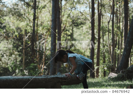 Cute little girl walking on a log in the park. child on the balance beam. Play is learning in childhood. 84676942