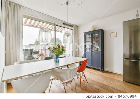 Stylish dining area with a chic chandelier and a vase of flowers on the table Stylish dining area with a chic chandelier and a vase of flowers on the table 84676994
