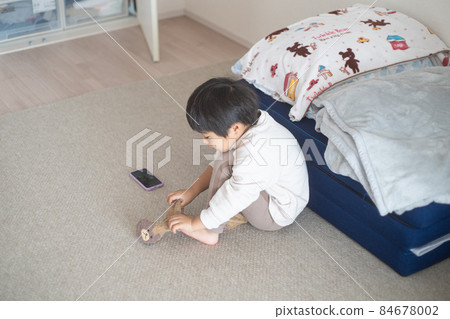 一個 4 歲的孩子穿著襪子，在陽光明媚的房間裡用智能手機聊天 84678002