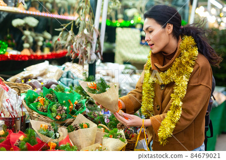 Woman choosing christmas decorations at fair Woman choosing christmas decorations at fair 84679021