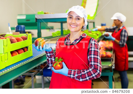 Woman worker standing in warehouse holding peaches 84679208