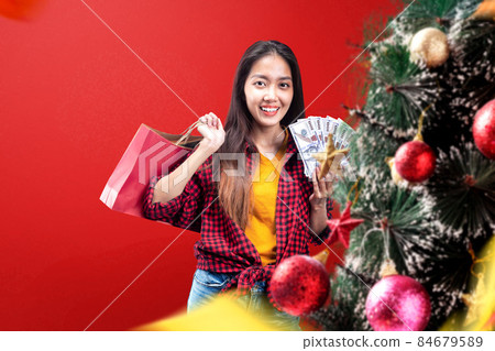 Decorated Christmas tree with Asian woman holding money and shopping bag 84679589