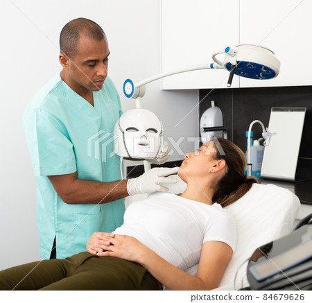 Cosmetician explaining phototherapy procedure to female client Cosmetician explaining phototherapy procedure to female client 84679626