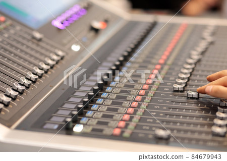 hand adjusting faders on an audio mixing console 84679943