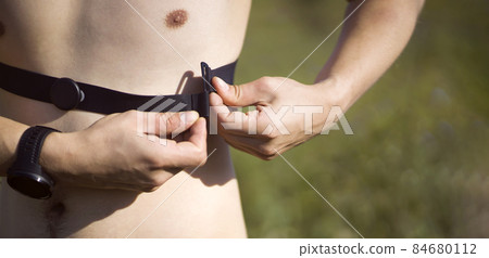 Man puts on a heart rate monitor before jogging. Man puts on a heart rate monitor before jogging. 84680112