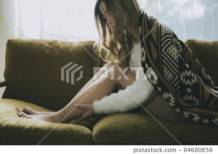Female massaging legs on the couch Female massaging legs on the couch 84680656