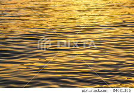 Golden sea waves in sunset glow as surface background. Summer holidays and coastal nature concept Golden sea waves in sunset glow as surface background. Summer holidays and coastal nature concept 84681396
