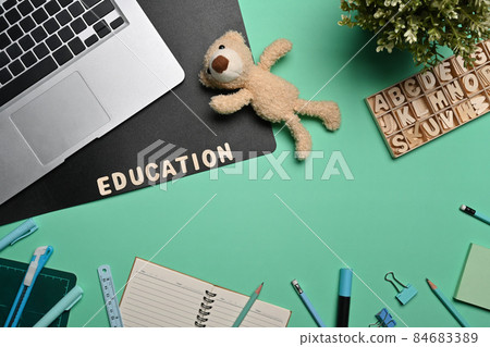 Laptop computer and various stationery on green background. 84683389