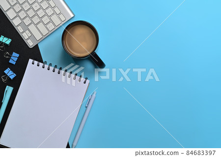 Flat lay empty notebook, coffee cup and keyboard on blue background. 84683397