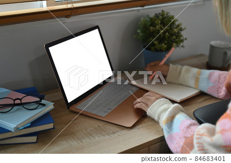 Young woman making notes on notebook and using computer laptop at home. Young woman making notes on notebook and using computer laptop at home. 84683401