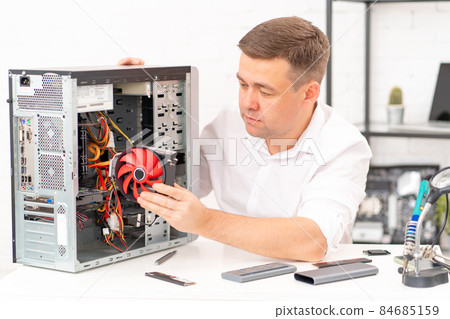 computer workshop. repairman installs a cooler in in a computer computer workshop. repairman installs a cooler in in a computer 84685159