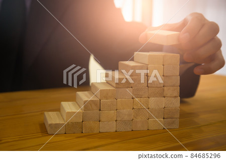 Business man gambling placing wooden block. Business concept investment target and growth success process background present financial information planning, risk and marketing strategy analysis. Business man gambling placing wooden block. Business concept investment target and growth success process background present financial information planning, risk and marketing strategy analysis. 84685296