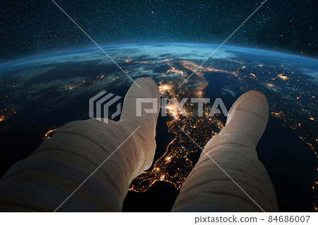 Spaceman sits and looks at the blue planet earth with night lights of cities from space. Astronaut feet on the background of the earth. Cosmos wallpaper. Man resting in orbit Spaceman sits and looks at the blue planet earth with night lights of cities from space. Astronaut feet on the background of the earth. Cosmos wallpaper. Man resting in orbit 84686007