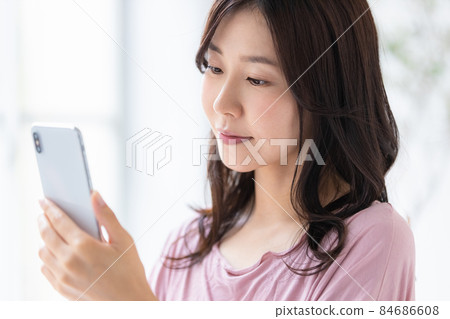 穿著便裝並操作智能手機的女性 84686608