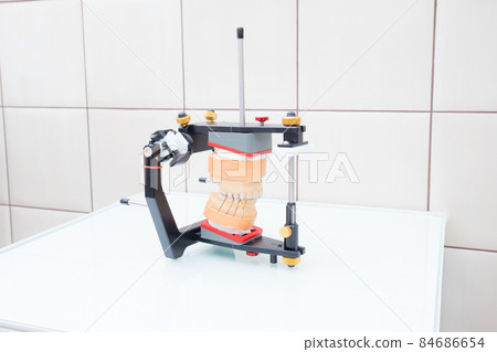 Model of the jaw in the articulator in the dental laboratory white background. Concept of modern dentistry and orthopedics 84686654