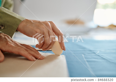 Dressmaker measures cloth on the table in workshop 84688320