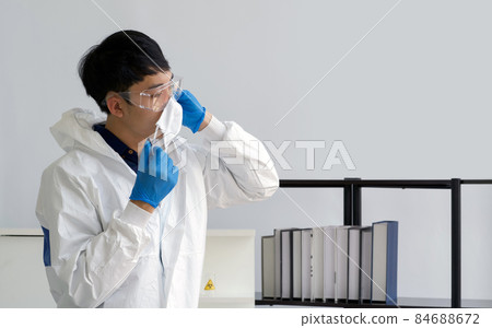 Asian scientist in virus protective cloth waring face mask before starting the experiment in a scientific laboratory. 84688672
