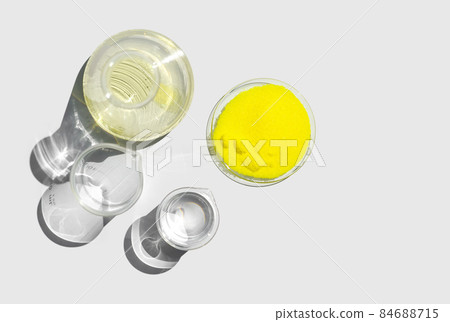 Closeup chemical ingredient on white laboratory table. Potassium Chromate powder in Chemical Watch Glass place next to beaker with alcohol and Erlenmeyer flask. Top View 84688715