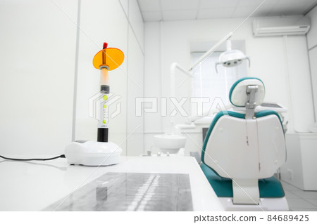Dental polymerization lamp with UV light and laser. Stomatological instrument in the dentist clinic. Medicine, health, stomatology concept. 84689425