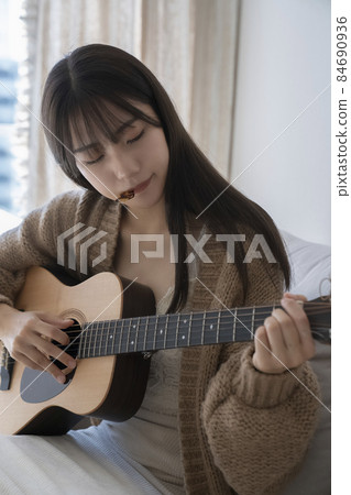 A woman playing the guitar A woman playing the guitar 84690936