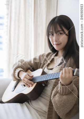 A woman playing the guitar A woman playing the guitar 84690983