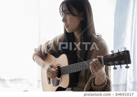 A woman playing the guitar 84691017