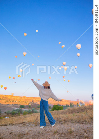 Happy woman during sunrise watching hot air balloons in Cappadocia, Turkey Happy woman during sunrise watching hot air balloons in Cappadocia, Turkey 84691114