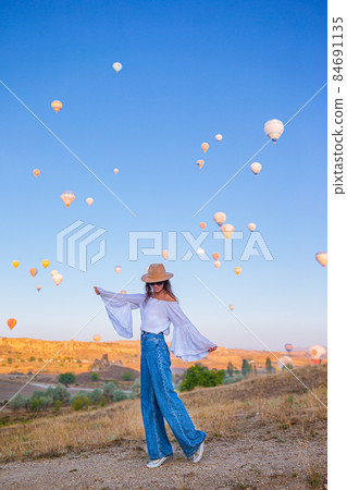 Happy woman during sunrise watching hot air balloons in Cappadocia, Turkey 84691135