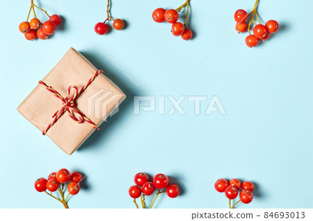 Christmas gift box on a blue background decorated with rowan berries with copy space Christmas gift box on a blue background decorated with rowan berries with copy space 84693013