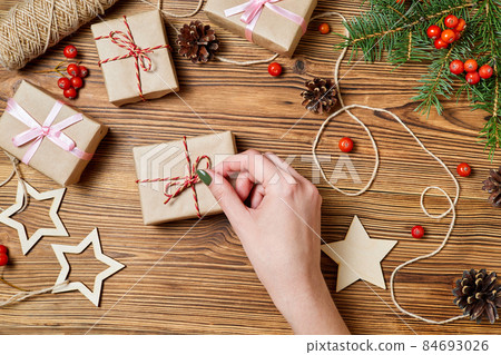 Girl unties the rope on the gift box on the background of christmas accessories Girl unties the rope on the gift box on the background of christmas accessories 84693026