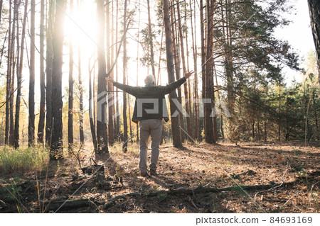 Overjoyed old man feeling freedom while traveling in forest during the autumn Overjoyed old man feeling freedom while traveling in forest during the autumn 84693169
