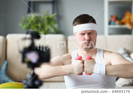 Strong middle aged man train on camera using pink dumbbells 84693179