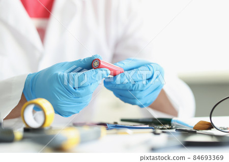 Handyman in gloves repair something electronical holding red battery detail Handyman in gloves repair something electronical holding red battery detail 84693369